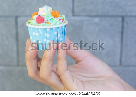 Image of human hand holding cup cake