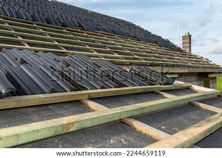 Roof ceramic tile arranged in packets on the roof on roof battens. Preparation for laying tiles on a boarded roof. Royalty-Free Stock Photo #2244659119
