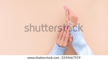 female hands with french manicure on beige background moisturizing hands with cream on hand Royalty-Free Stock Photo #2244667959