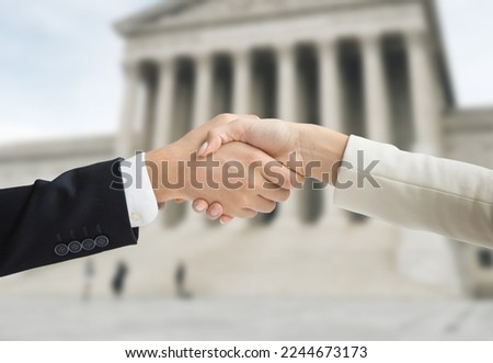 Two lawyers shaking hands outside the court building Royalty-Free Stock Photo #2244673173