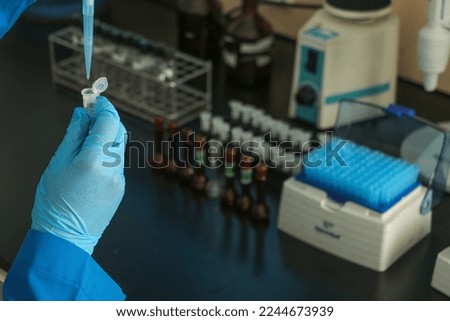 a pharmacist's hand testing a substance that has been studied with blue medical gloves in the laboratory
