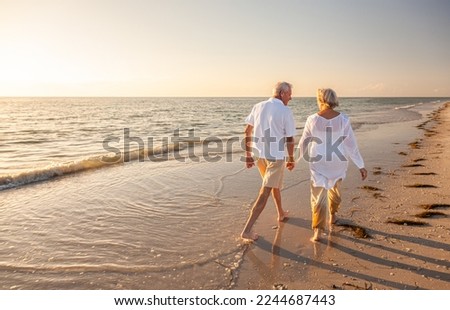 Happy senior man and woman old retired couple walking and holding hands on a beach at sunset, s3niorlife Royalty-Free Stock Photo #2244687443