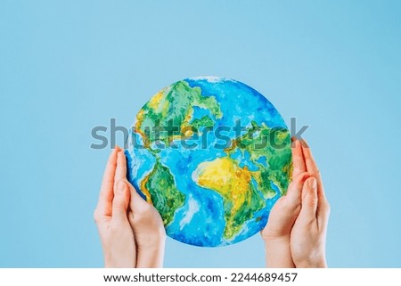 Mother and son holding a picture of the Earth on a blue background. Save the planet. The concept of environmental protection and energy saving