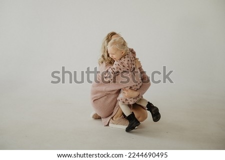 Mom kisses and hugs her daughter in the studio.