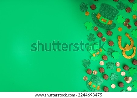 St Patrick flatlay background with shamrock clover leaves, leprechaun hat decor, golden coins and chocolates in form of symbol of st. patrician day