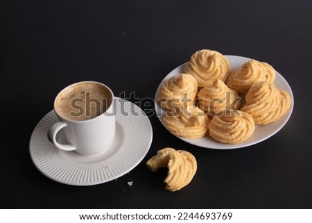 photo meringue cake on a white plate and a coffee cup with coffee on a black background