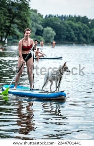 Sportive girl paddling on sup board with her dog. Summer vacation theme