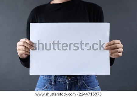 Blank white paper for mock up and text space holded by hands of woman on dark gray background. 