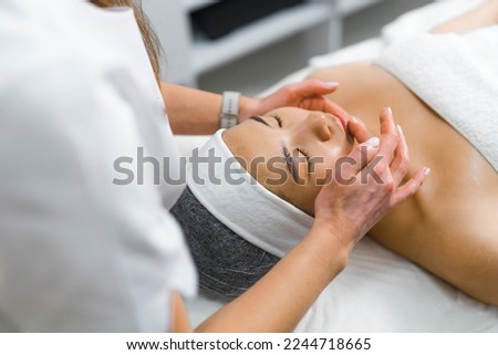 A beautician massaging a woman's face. High-angle shot taken from the corner. Beauty concept. High quality photo