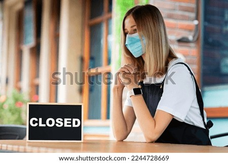 Caucasian waitress woman wearing medical mask and SORRY WE'RE CLOSED. Coronavirus pandemic. Government shutdown of restaurants, shopping stores, non essential services
