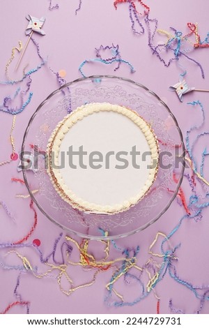 Birthday cake with empty space for text or picture. Beautiful white cake over lilac background with festive decorations. Top view, copy space, flat lay