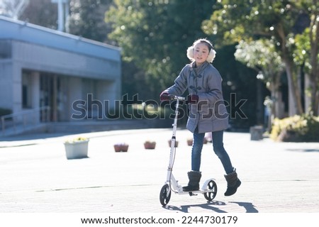 Girl plays on a kick scooter Royalty-Free Stock Photo #2244730179