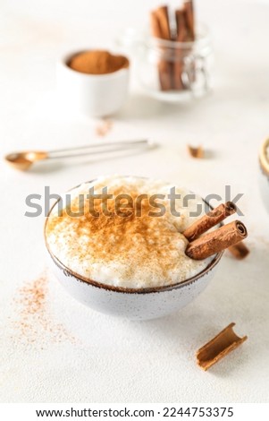 Bowl with delicious rice pudding and cinnamon on white table Royalty-Free Stock Photo #2244753375