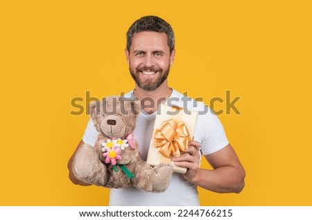 glad man with gift for valentine day. photo of man holding valentine gift of box and toy.