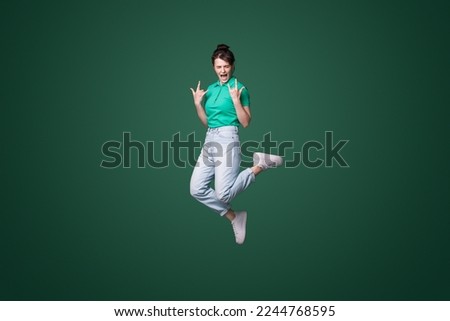 Full body photo of crazy funky woman jump up in air making horned signs screaming isolated on green color background