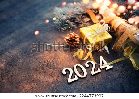 happy new year 2024 card with bottle of champagne and present gift over dark stone background