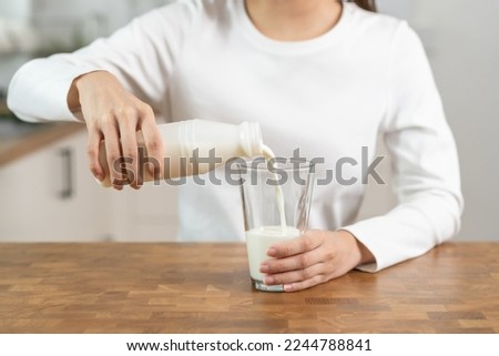 Health care, asian young woman, girl hand pouring of fresh, dairy milk from bottle into glass, drinking and eating breakfast in morning at kitchen home. Calcium, protein for healthy lifestyle people