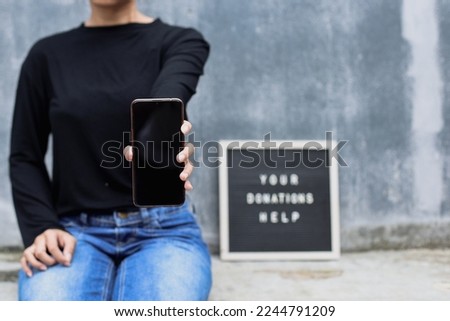 Woman showing blank screen smartphone for mock up or text space. Donation and charity concept.   