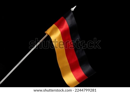 The German flag on a black background develops and flies in the wind