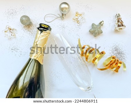 A bottle of champagne and glasses for the New Year. Sequins and Christmas decorations.