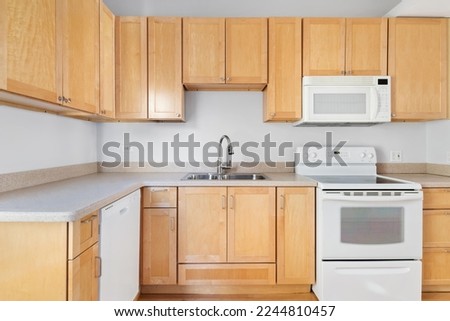 Builder Grade Kitchen with Oak Shaker Cabinets and White Appliances. Basic Kitchen in rental apartment. Royalty-Free Stock Photo #2244810457