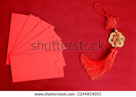 Chinese New Year, red envelope and lucky decorative golden coins with Chinese blessing words means happiness, richness and good fortune on red background, lucky item oriental with space copy