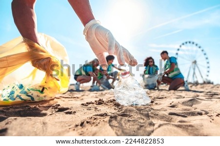 Group of eco volunteers picking up plastic trash on the beach - Activist people collecting garbage protecting the planet - Ocean pollution, environmental conservation and ecology concept Royalty-Free Stock Photo #2244822853