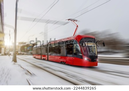 Red tram rushes through the city in winter motion blur effect