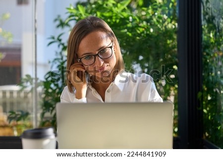 Cheerful mature businesswoman working from cafe, having online video call using laptop. High quality photo