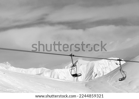 Chair lift at ski resort. Caucasus Mountains, Georgia, region Gudauri. Snowy high mountains in winter. Black and white toned image. Royalty-Free Stock Photo #2244859321