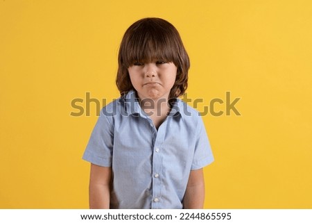 Kids depression. Studio portrait of unhappy little boy almost crying, feeling abandoned and upset, orange background, free space