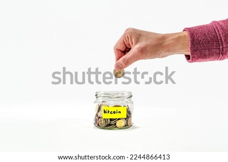 Man putting money into Close up glass jar with coins, moneybox, penny or piggy bank. Saving money for bitcoin. Saving money penny bank on white background. Yellow education sticker on it.