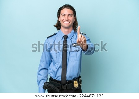 Young police caucasian man isolated on blue background showing and lifting a finger