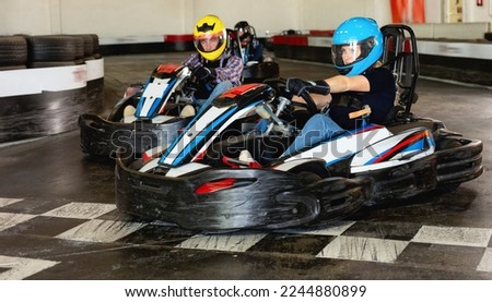 Group of positive smiling people driving go-carts at racing track Royalty-Free Stock Photo #2244880899