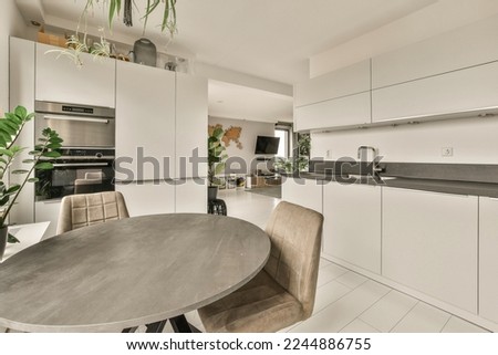 a kitchen and dining area in a modern home with white cabinets, marble countertops, stainless appliances and a round table