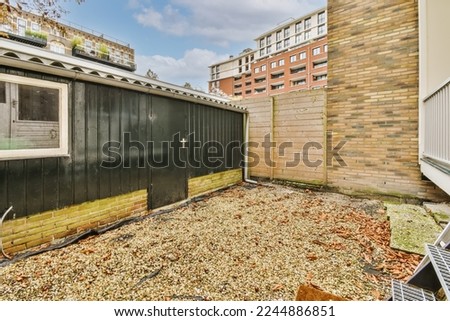 an outside area with some leaves on the ground and brick buildings in the background photo is taken from behind it Royalty-Free Stock Photo #2244886851