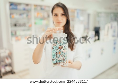 Health care professional woman working at a pharmacy drugstore.Friendly pharmacist holding pills jar. Medication and therapy expertise. Pharmaceutical service.Prescription drug administration Royalty-Free Stock Photo #2244888117
