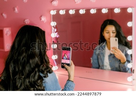 Young teen girl standing in front of a pink wall