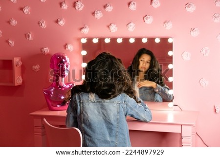 Young teen girl standing in front of a pink wall
