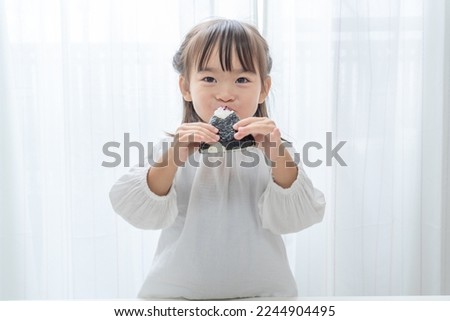 Cute asian child eating rice ball