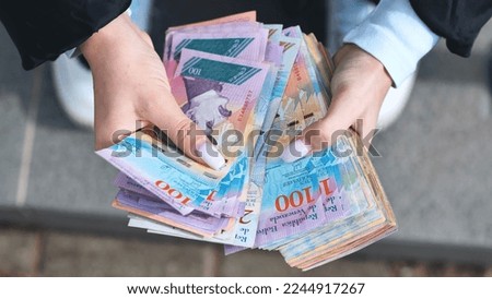 A girl counts old Venezuelan money. Royalty-Free Stock Photo #2244917267