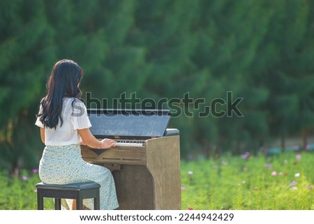 a girl is playing piano in flowers garden 