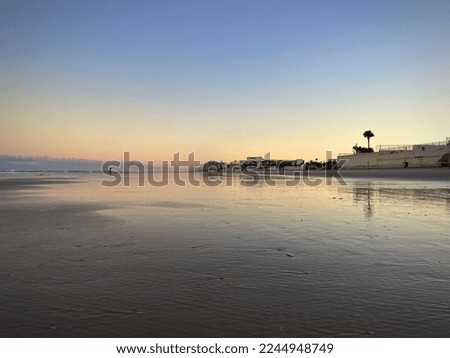 Daytona beach shoreline during low tide sunset with standing water over wet sand. Royalty-Free Stock Photo #2244948749