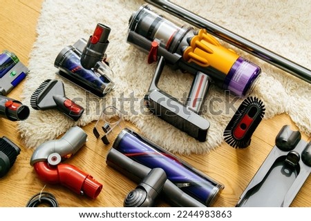 Knolling style above modern wireless Vacuum Cleaner powerful cordless colorful cyclonic dust collection - all accessories on the wooden parquet floor with Irish Sheepskin rug Royalty-Free Stock Photo #2244983863