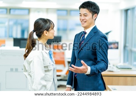 A Japanese woman in work clothes and a Japanese man in a suit Royalty-Free Stock Photo #2244984893