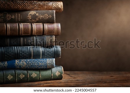 Old books on wooden desk and ray of light. Bookshelf history theme grunge background. Concept on the theme of history, nostalgia, old age. Retro style. Old book as a symbol of knowledge. Royalty-Free Stock Photo #2245004557