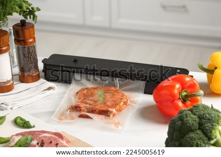 Sealer for vacuum packing with meat in plastic bag on white kitchen table Royalty-Free Stock Photo #2245005619