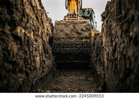 Cropped picture of an excavator digging hole on construction site. Royalty-Free Stock Photo #2245009013