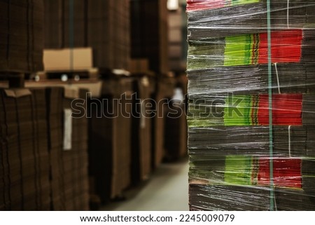Stocks of unpacked cardboard boxes wrapped in transparent stretch film. Stocks of cardboard for packaging fresh fruits and vegetables. Stocks of raw materials and preparing for sorting