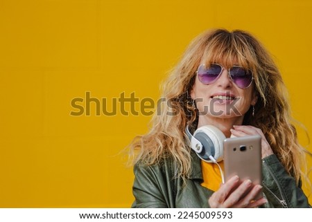 mature woman on yellow wall with headphones